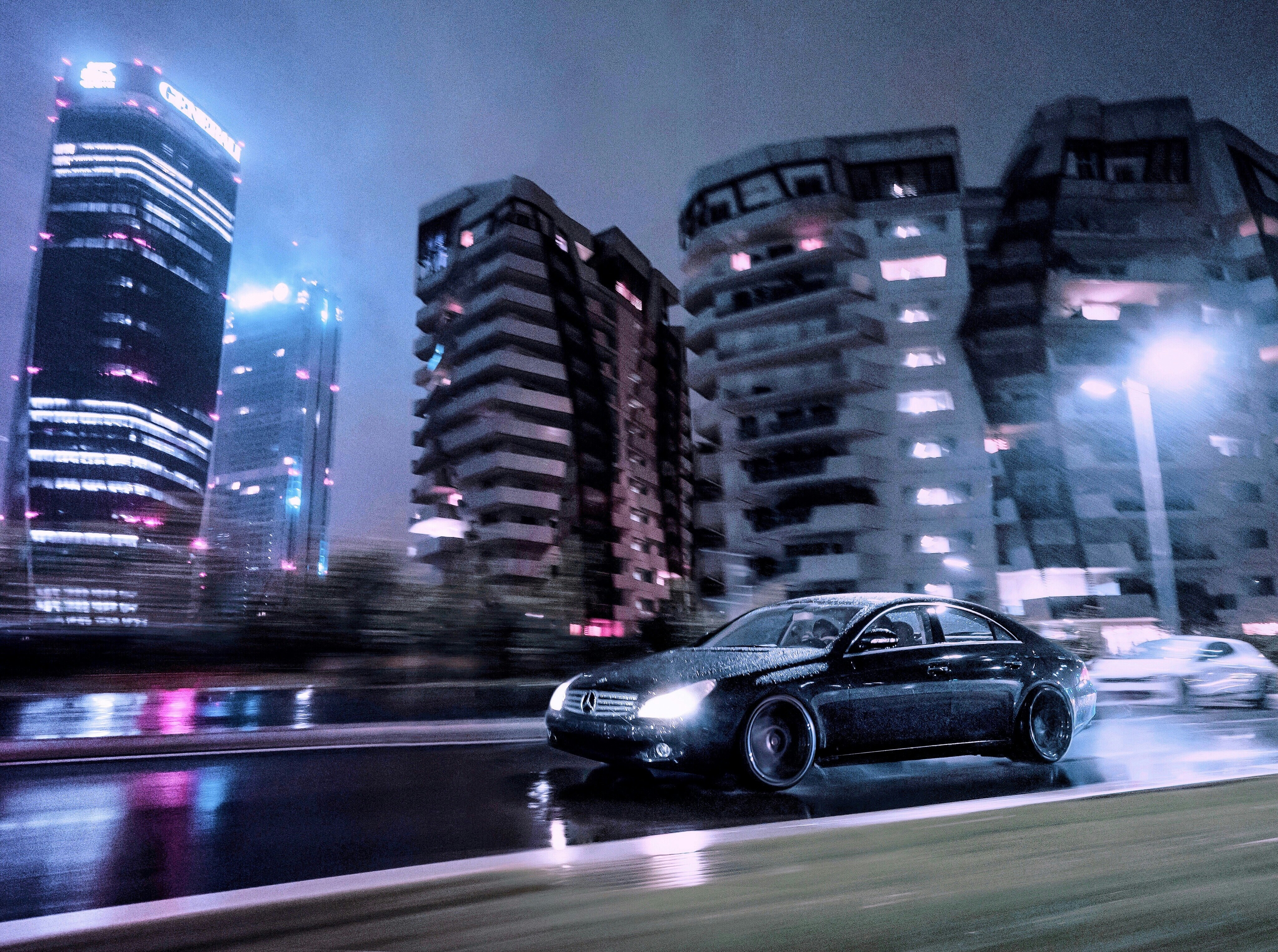 black sedan on road near high rise buildings during night time